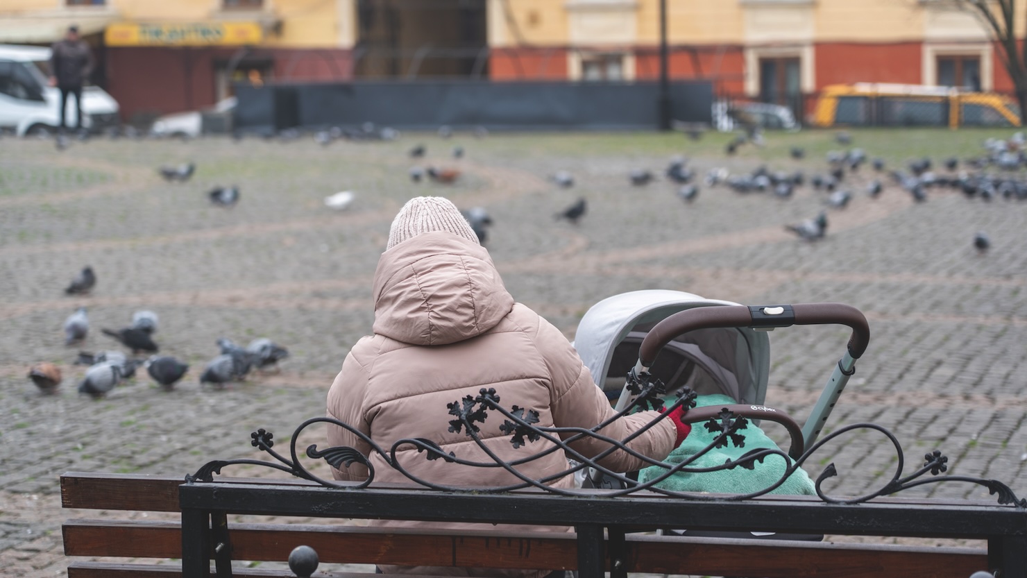 person with baby carriage in town square