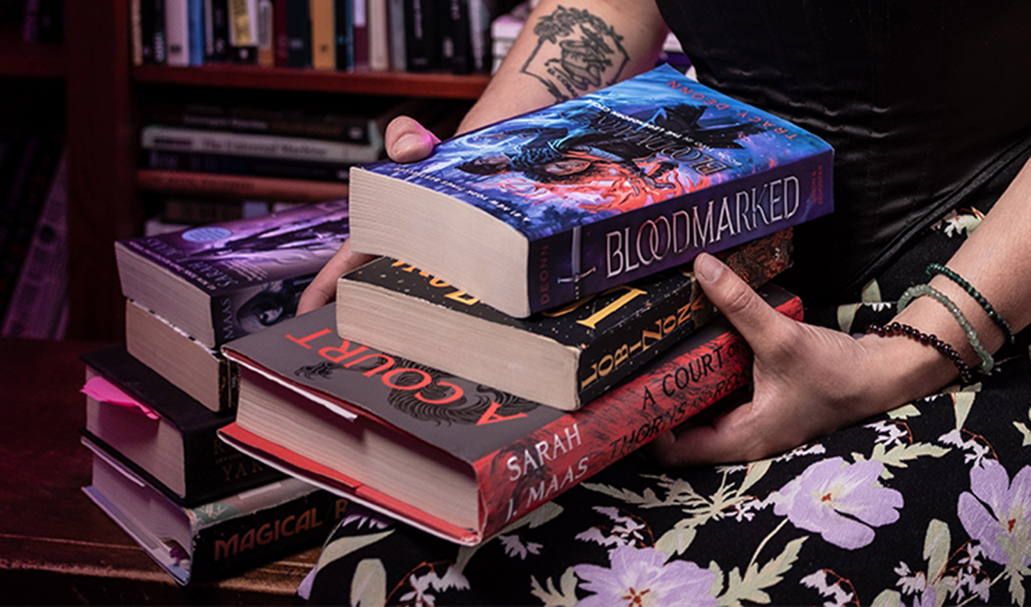 Woman holding stack of fantasy books