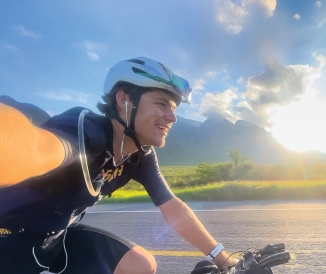 Man taking a selfie while riding bicycle on highway with mountains in background