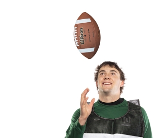 Man wearing a vest tosses football in air