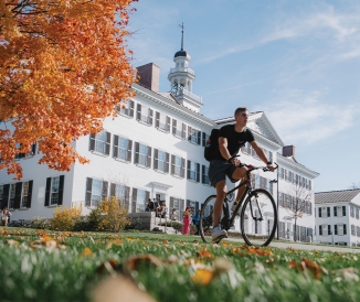Person riding bike across campus in autumn