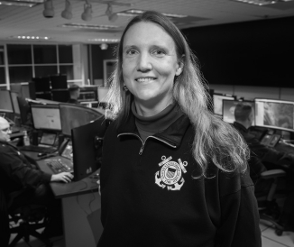 Black and white photo of woman in office wearing Coast Guard sweatshirt