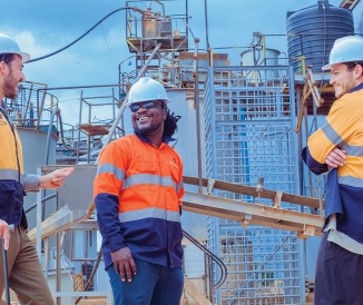 Three men wearing hard hats at an industrial plant