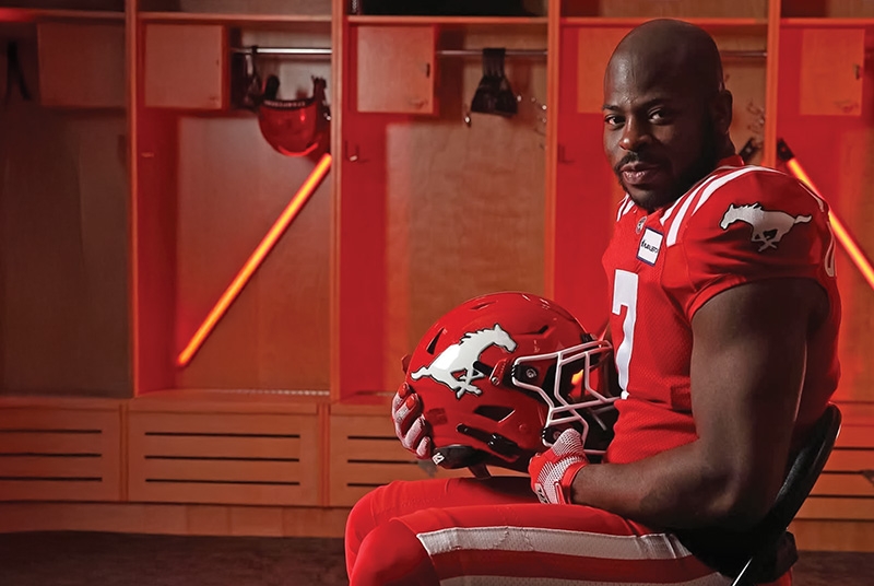 Football player sitting in locker room, holding helmet