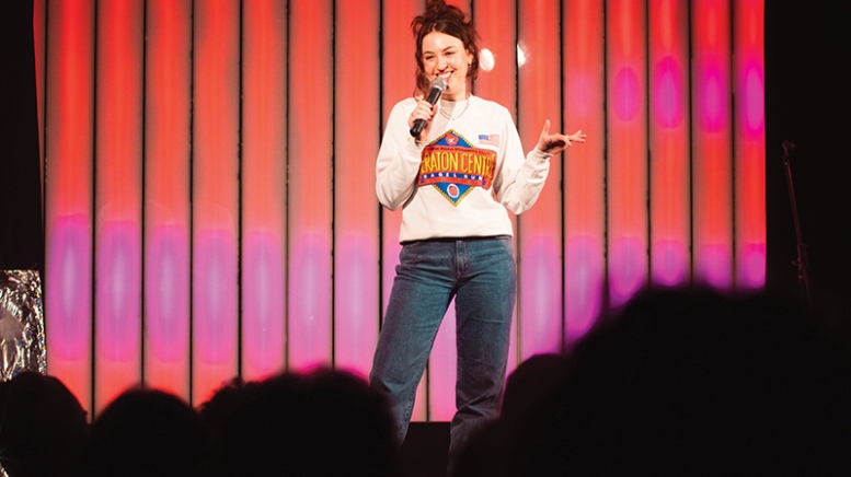 Woman holding microphone on stage in front of crowd