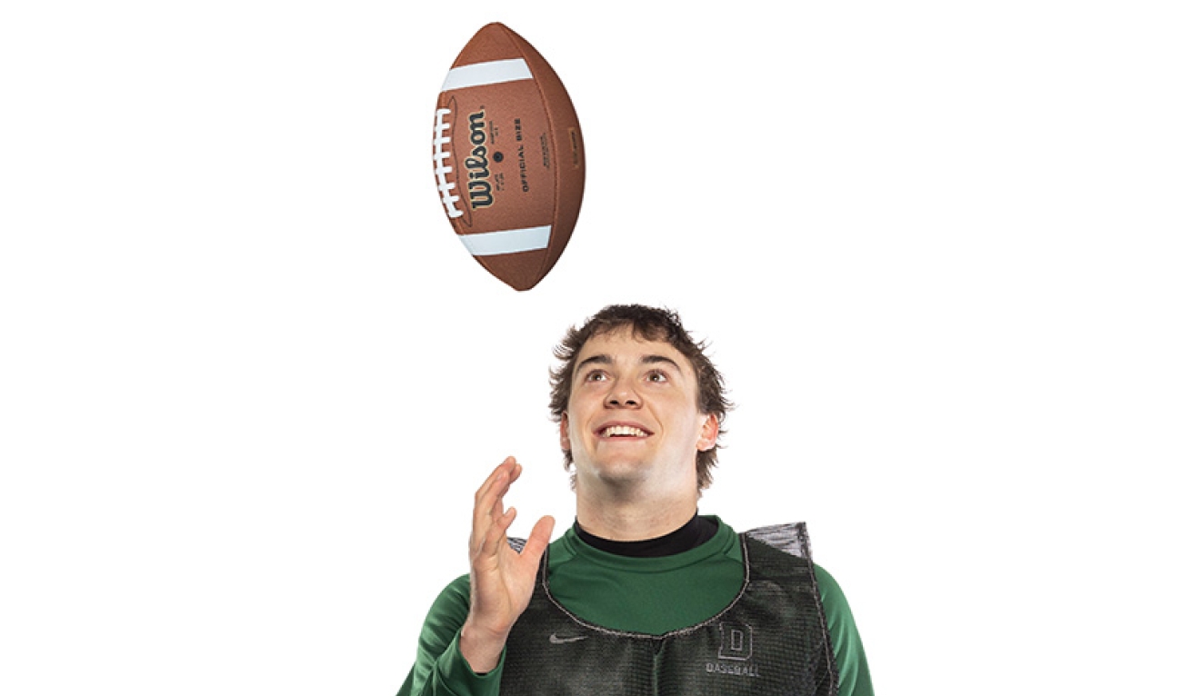 Man wearing a vest tosses football in air