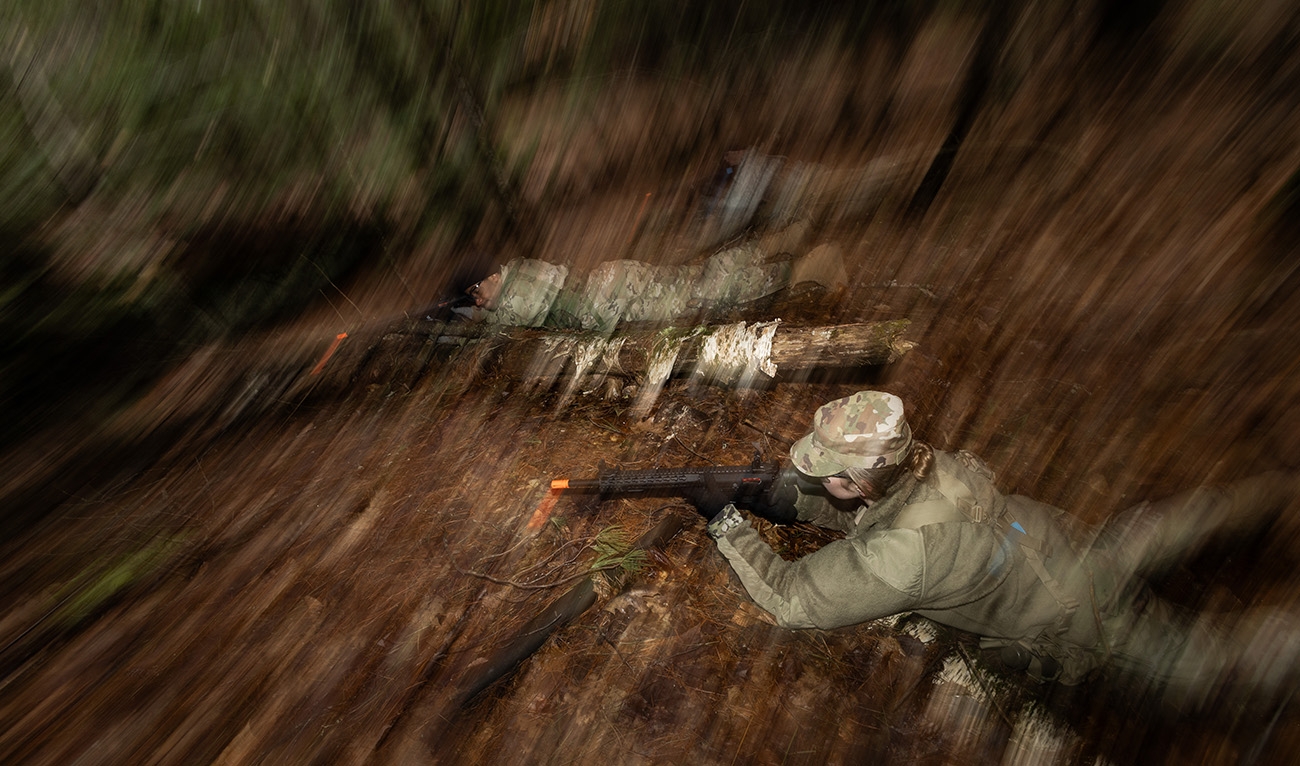 Cadets on ground in woods, holding guns