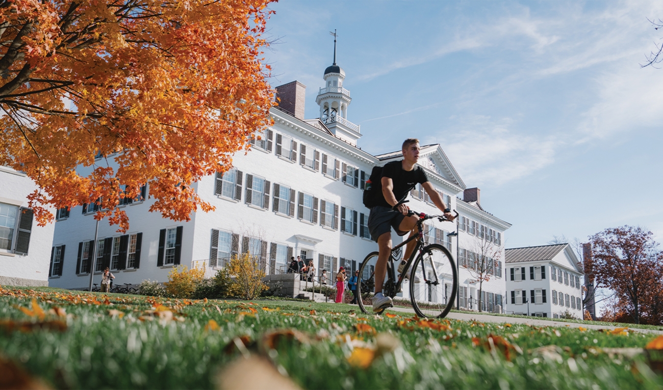 Person riding bike across campus in autumn