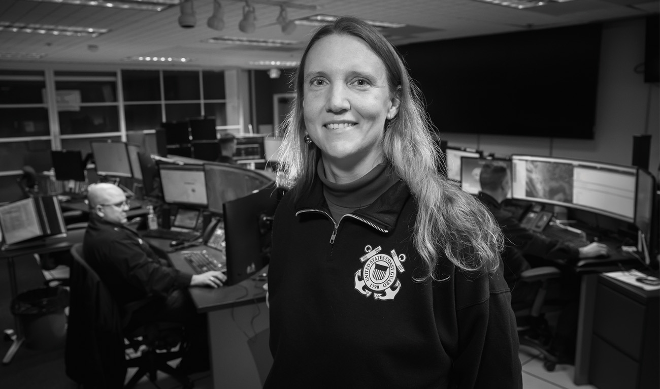 Black and white photo of woman in office wearing Coast Guard sweatshirt