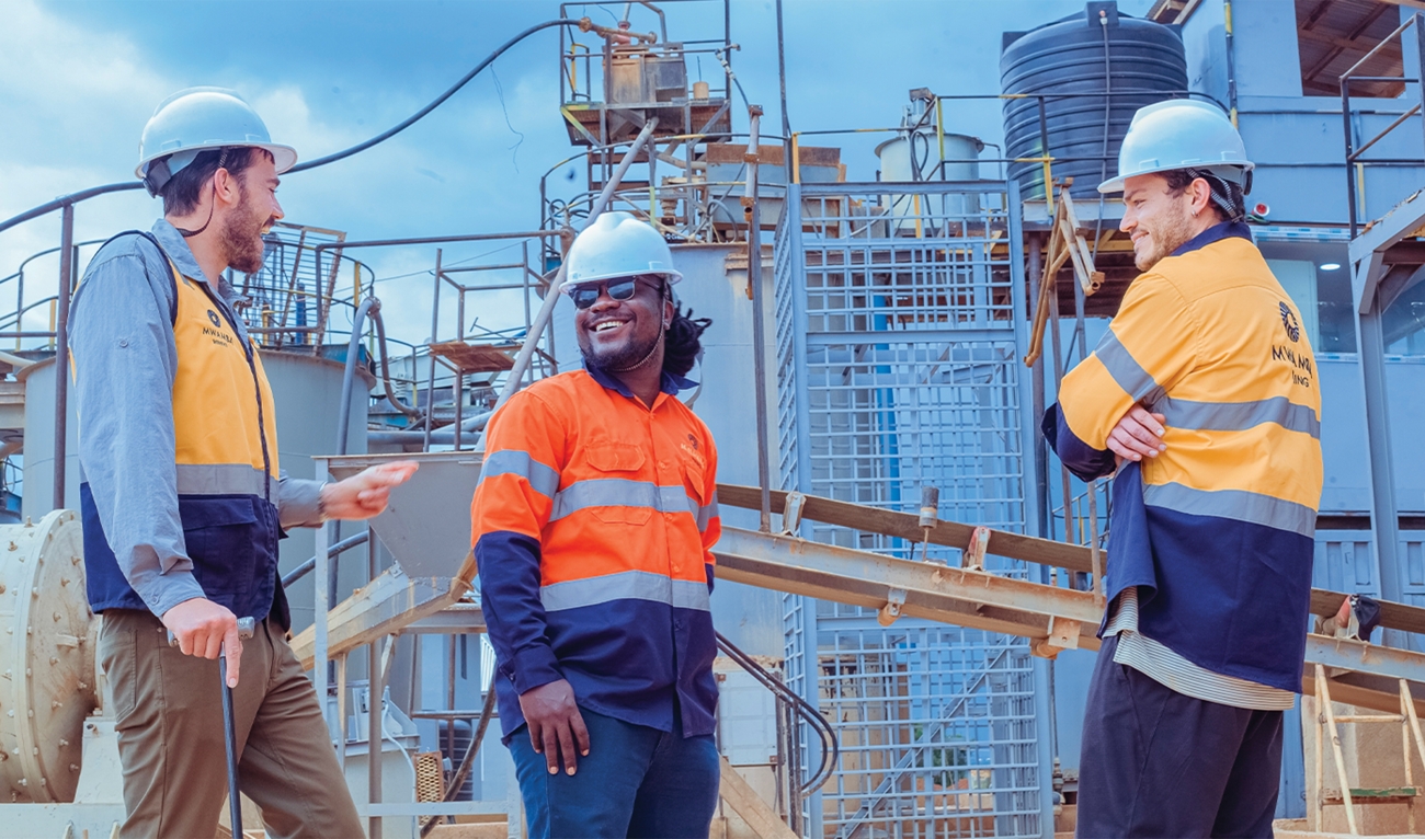 Three men wearing hard hats at an industrial plant