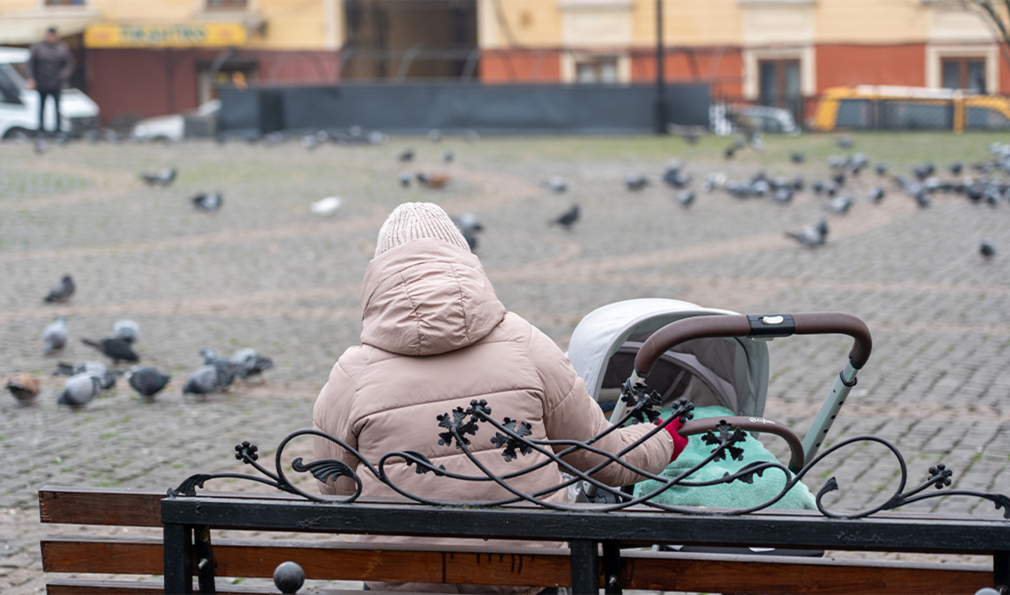 Woman sitting on bench with baby stroller
