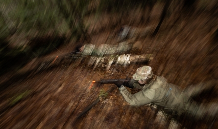 Cadets on ground in woods, holding guns