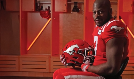Football player sitting in locker room, holding helmet