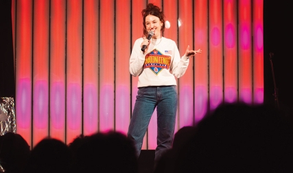 Woman holding microphone on stage in front of crowd