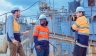 Three men wearing hard hats at an industrial plant
